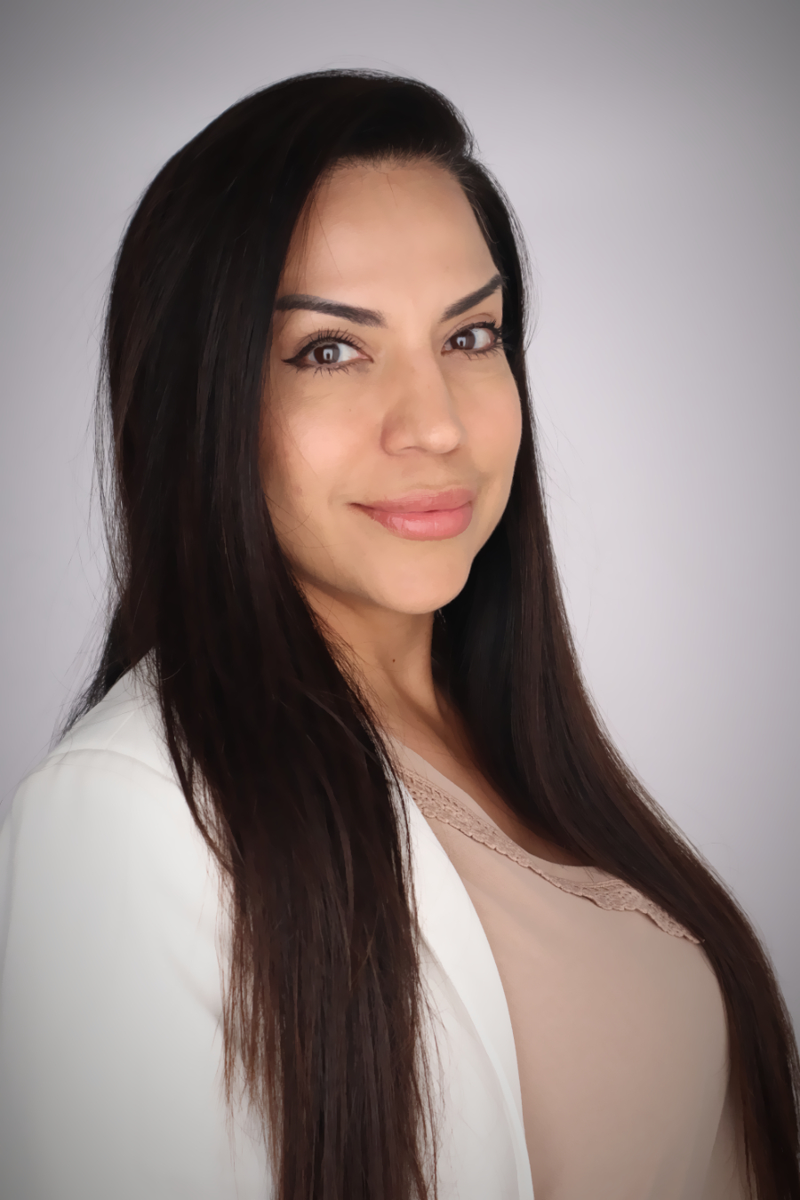 Woman smiling. She has long dark hair and is wearing a white sweater with pink shirt