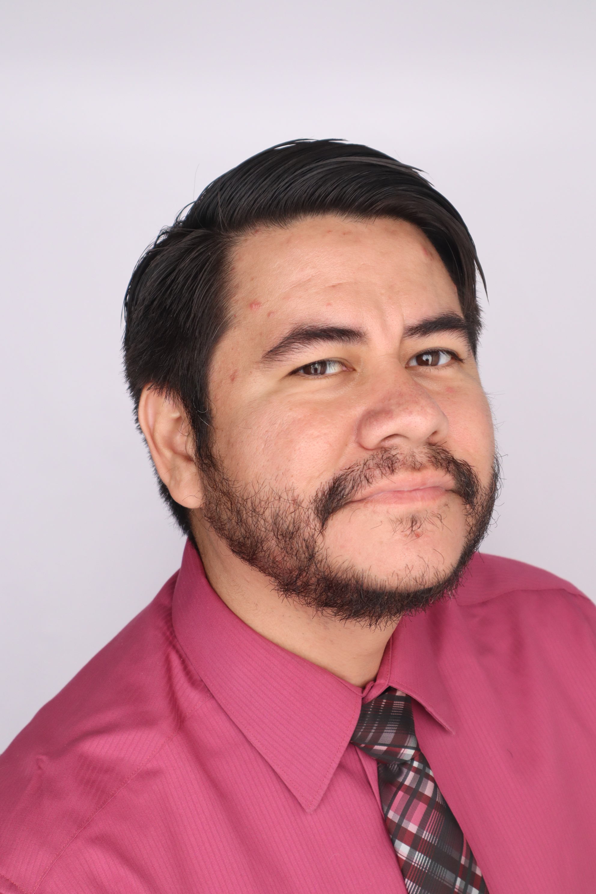 Man with facial hair smiling. Wearing a red shirt and tie