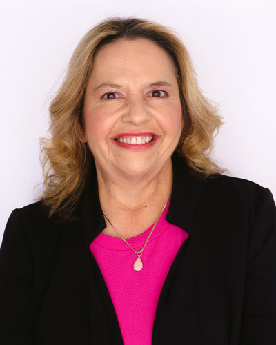 Smiling woman wearing a black blazer and pink top.